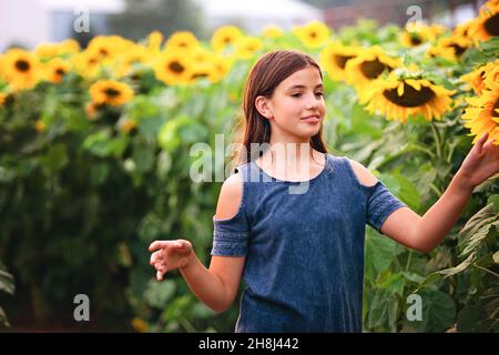 Glückliches Tween Mädchen in einem Sonnenblumenfeld. Stockfoto