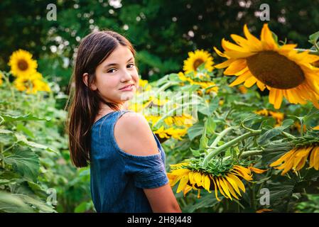 Glückliches Tween Mädchen in einem Sonnenblumenfeld. Stockfoto