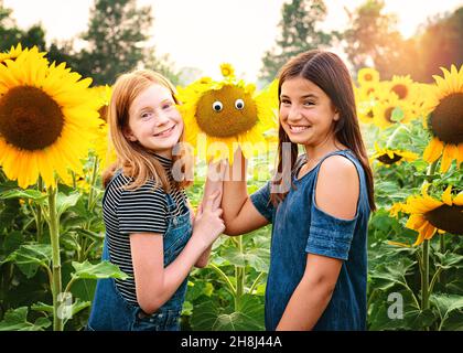 Zwei glückliche Tween Mädchen in einem Sonnenblumenfeld. Stockfoto