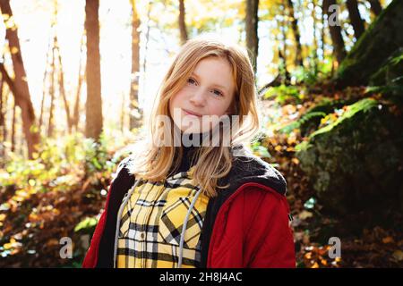 Rothaarige Tween Girl Wandern in den Herbstwäldern. Stockfoto