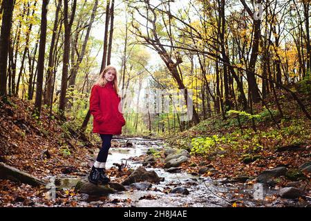 Rothaarige Tween Girl Wandern in den Herbstwäldern. Stockfoto