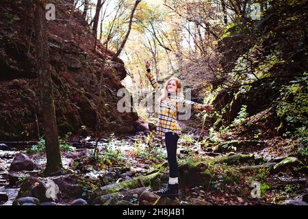 Rothaarige Tween Girl Wandern in den Herbstwäldern. Stockfoto