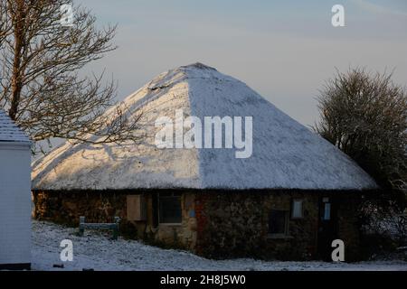 Reetdach einer Hütte im Pagham Harbour Nature Reserve, gesehen bedeckt mit einem Stauben von Schnee im November 2021. Stockfoto