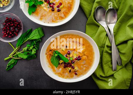 Ansicht der marokkanischen gerösteten Kürbissuppe von oben: Geröstete Kürbissuppe, garniert mit Minzblättern, Granatapfelkernen und gehackten Pistazien Stockfoto