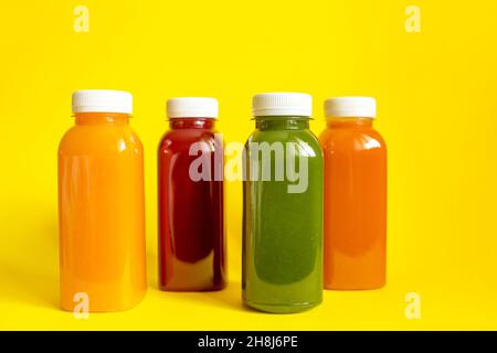Frische Säfte oder Smoothies von Obst und Gemüse in Flaschen auf gelbem Hintergrund. Das Konzept einer gesunden Ernährung, Ernährung oder Entgiftung. Flach liegend, Draufsicht Stockfoto