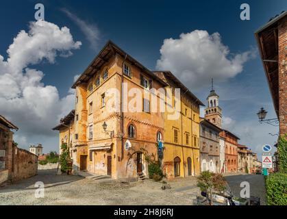 Saluzzo, Cuneo, Italien - 19. Oktober 2021: Salita al Castello Straße mit alten bunten historischen Gebäuden und im Hintergrund der Bürgerturm (X Stockfoto