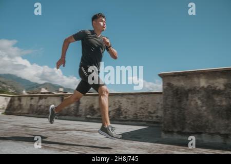 Junger, hübscher Kerl, der auf dem Dach eines Gebäudes läuft Stockfoto