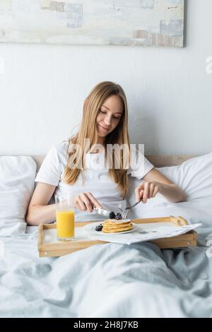 Eine erfreuende Frau, die im Bett gefrühstückt hat Stockfoto