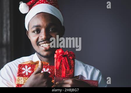 Afrikanischer Mann mit einer Geschenkbox für weihnachten mit einem Lächeln und glücklich Stockfoto