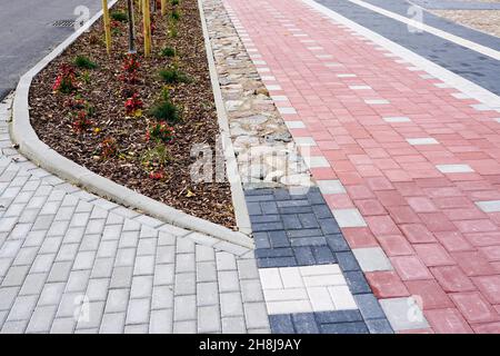 Neuer, moderner, farbenfroher gepflasterter Gehweg und Fahrradweg mit Kopfsteinpflaster in verschiedenen Farben Stockfoto