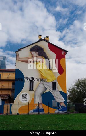 Mailand, Italien farbenfrohe Wandgraffiti. Street Art Wandgemälde des Künstlers Rosk, das ein junges Mädchen zeigt, das mit der Botschaft Open Your Future eine Wand schiebt. Stockfoto