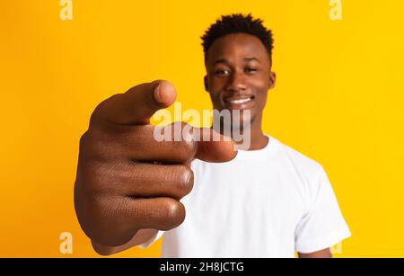 Positiver junger schwarzer Mann, der lächelt und mit dem Zeigefinger auf die Kamera zeigt und große Geste auf orangefarbenem Hintergrund zeigt Stockfoto