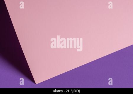 Unbeschriftete, pastellrosa Papierkarte mit Schatten auf violettviolettem Hintergrund. Abstrakt geometrische monochrom rosa Hintergrund mit Kopieplatz für Stockfoto