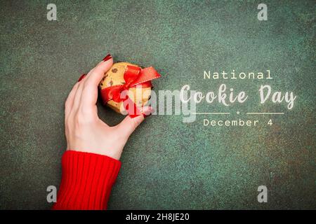 Nationaler Cookie-Tag, 4th. Dezember Hintergrund. Die Hand der Frau hält einen Stapel Schokoladenchips knusprige Kekse. Speicherplatz kopieren Stockfoto