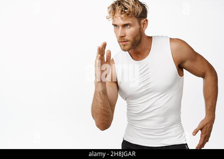 Bild eines gutaussehenden Joggers, der auf weißem Hintergrund läuft, beim Laufen trainiert und entschlossen aussieht Stockfoto