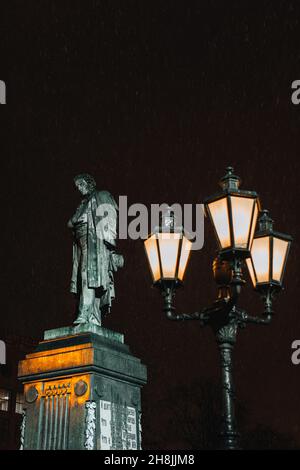 Denkmal des russischen berühmten Dichters Alexander Puschkin auf dem Puschkin-Platz, Moskau, Russland. Brennende Laterne im Abendlicht und fallender Schnee Stockfoto