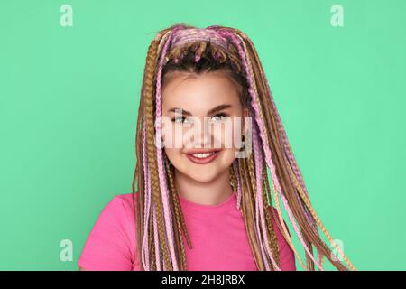 Frau mit Dreadlocks lächelt auf grünem Hintergrund Stockfoto