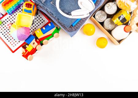 Spende, Wohltätigkeitskonzept. Spendenboxen mit Kinderkleidung und Spielzeug, Lebensmittelspenderbox mit Lebensmittelprodukten auf weißem Tisch. Draufsicht, Kopierbereich Stockfoto