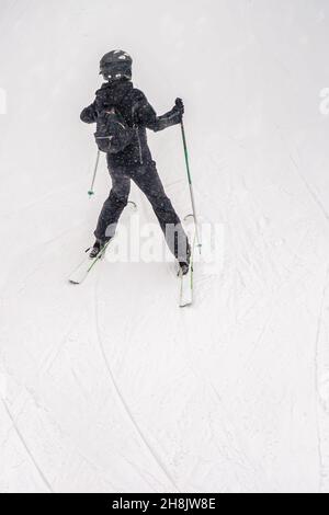 Rückansicht des jungen Athleten auf Skiern, Skipiste, verschwommener selektiver Fokus. Wintersport Stockfoto