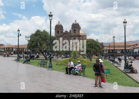 Hauptplatz und Kathedrale oder Kirche im Cusco Peru Park Menschen, die auf Bänken sitzen, Lichter, Blumen, alte Geschichte, historische Bänke Sitze Stockfoto