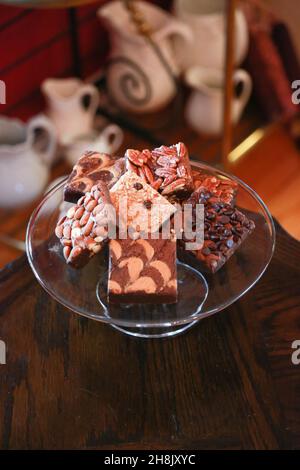 Stapel Brownies auf Glasplatte auf Holztisch in Zimmereinstellung Stockfoto