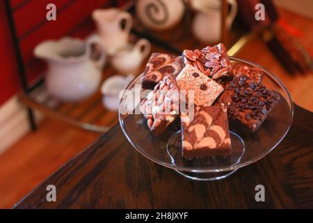 Stapel Brownies auf Glasplatte auf Holztisch in Zimmereinstellung Stockfoto