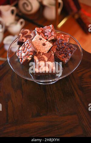 Stapel Brownies auf Glasplatte auf Holztisch in Zimmereinstellung Stockfoto