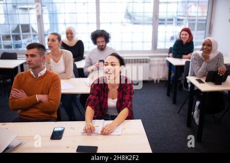 Multiethnische Studenten hören einem Dozenten in einem Klassenzimmer zu. Intelligente junge Menschen studieren an einer Hochschule. Stockfoto