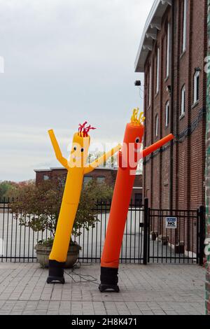 Leuchtend gelbe und orangefarbene Marketing-Ballons tanzen vor der alten Ziegelmühle am Flussufer in Ipswich, Massachusetts Stockfoto