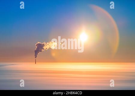 Rauch aus dem Hochrohr des Kraftwerks über den Wolken, Luftaufnahme. Aufsteigender Rauch aus einem hohen Kamin eines thermischen Kraftwerks über einer niedrigen Lage von Tem Stockfoto