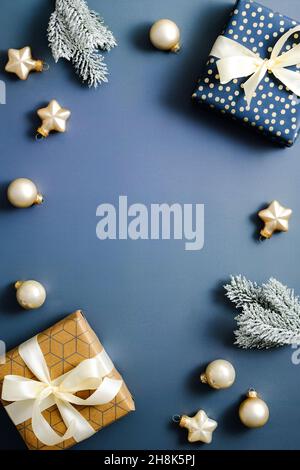 Weihnachtsrahmen aus Geschenkschachteln, Tannenzweigen, Kugeln, Stern auf blauem Hintergrund. Fröhliches Weihnachtsposterdesign. Stockfoto