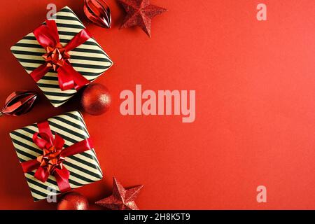 Weihnachtliche Rahmenbordüre aus Geschenkschachteln, Sternen, Kugeln auf rotem Hintergrund. Flach liegend, Draufsicht, Kopierbereich. Stockfoto