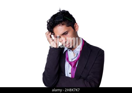 Ein Geschäftsmann mit zerzausten Krawatten und tiefgründigen Gedanken kratzt sich beim Blick nach unten den Kopf. Junge Erwachsene Geschäftsmann isoliert auf ganz weißem Hintergrund. Stockfoto