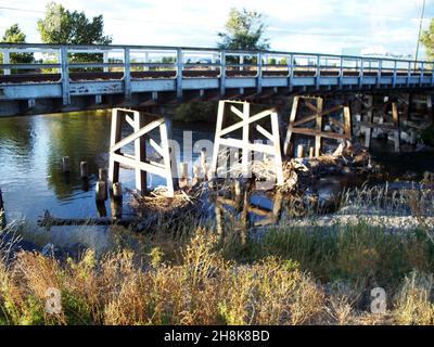 Die alte Holzbrücke läuft über einen kleinen Teich mit der Sonne auf der linken Seite des Fotos. Stockfoto