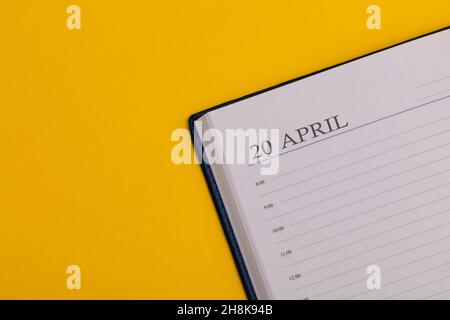 Notizblock oder Tagebuch mit dem genauen Datum auf gelbem Hintergrund. Kalender für April 20 - Frühlingszeit. Platz für Text. Stockfoto