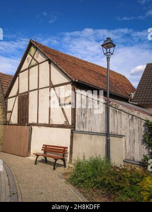 Vertikale Aufnahme eines alten Hauses mit einem Ziegeldach gegen einen blau bewölkten Himmel an einem sonnigen Tag Stockfoto