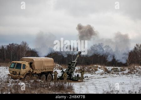 Soldaten der Nationalgarde der US-Armee feuern die M777 Haubitze während einer US-slowakischen Live-Feuer-Übung im Bemowo Pikie Training Area, Polen, 30. November 2021. Die Dachs-Batterie des Dunklen Gewehr trainierte zusammen mit dem selbstfahrenden Haubitzer-Bataillon der slowakischen Bodentruppe aus dem Jahr 21st während der Übung zur Verbesserung der Interoperabilität und der multinationalen Kampfbereitschaft zur Unterstützung des NATO-Bündnisses. (USA Armeefoto von PFC. Jacob Bradford) Stockfoto