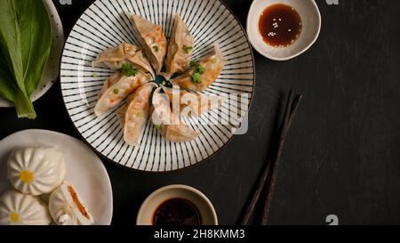 Gedünstetes Schweinefleisch, chinesische Knödel, Fleisch- und Gemüsebuns, Sojasauce, Essstäbchen und frisches Gemüse auf dem Tisch. Draufsicht Stockfoto