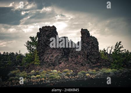 Blick auf Felder mit Lava und Pflanzen am Horizont, Lavahügel, vulkanische Landschaft an den Kratern des Moon National Monument & Preserve Stockfoto