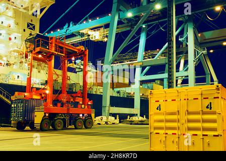 Portalkran, Radträger, Container. Schiffsanlegestelle oder Pier, Transportbehälter. Frachtschiff. Kommerzielle Laderampe Night USA Stockfoto