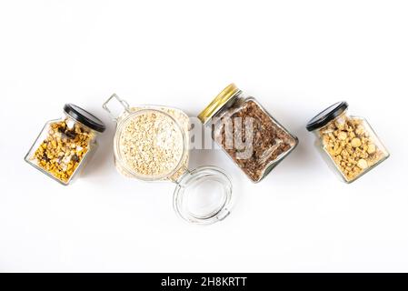 Draufsicht auf Gläser voller Hafer und verschiedenen knusprigen Granola - einfache, getrocknete Früchte, Nüsse und Schokolade. Gesundes Essen Konzept. Stockfoto