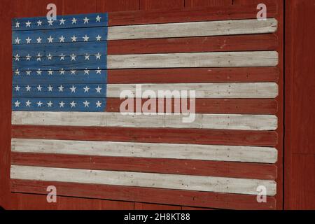 Eine hölzerne amerikanische Flagge auf der Seite einer roten Scheune. Stockfoto