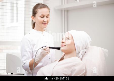 Junge Frau mit Mikrostrom galvanische Gesichtsbehandlung mit Elektroden zum Anheben Gesicht. Konzept Prävention von Akne und fettige Hautprobleme. Stockfoto