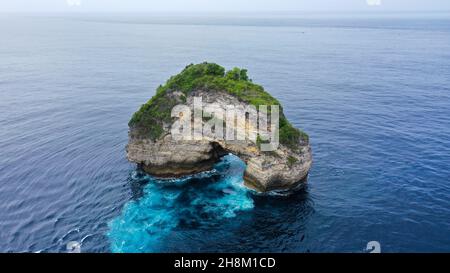 Natürlicher Felsbogen im Indischen Ozean, in der Nähe der Wild Coast auf Nusa Penida Island, Bali. Das große offene Loch an der Seite der Klippe wird von Wellen geformt. Wenn die Stockfoto