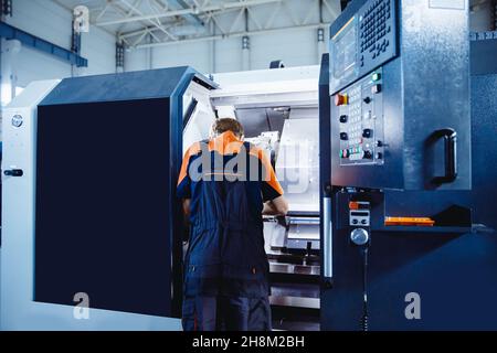 Junger männlicher Ingenieur, der CNC-Maschinen in der Eisenmetallfabrik betreibt Stockfoto