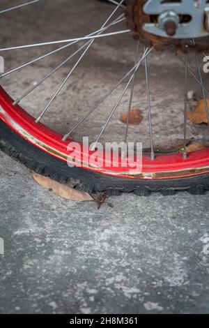 Nahaufnahme eines alten, flachen Fahrradreifens und Rost auf Zementhintergrund Stockfoto
