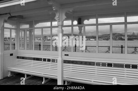 Nahaufnahme des Sitzes und des Tierheims am Swanage Pier, Dorset, England mit der Stadt im Hintergrund. Stockfoto