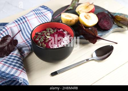 Eine Schüssel Smoothies mit Kürbiskernen und Zutaten für Smoothies - Apfel, Birne und Rote Bete. Gesundes veganes Dessert Stockfoto