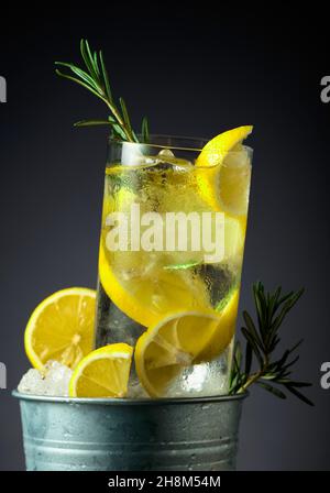 Gin-Tonic-Cocktail mit Eis, Zitrone und Rosmarin in einem Metalleimer mit Eis. Stockfoto