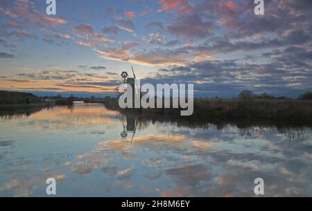 Ein Blick auf den Fluss Ant auf den Norfolk Broads im Herbst in der Abenddämmerung nach Sonnenuntergang mit einer ikonischen Windmühle aus How Hill, Ludham, Norfolk, England, Großbritannien. Stockfoto